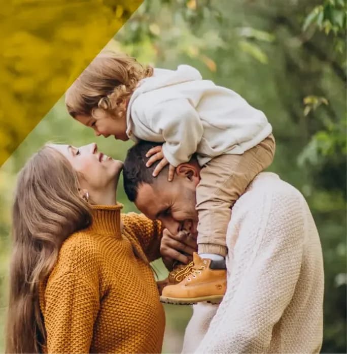 Una familia al aire libre: madre, padre y un niño sobre sus hombros